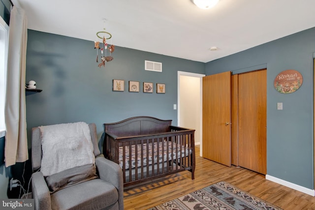 bedroom with a nursery area and light wood-type flooring