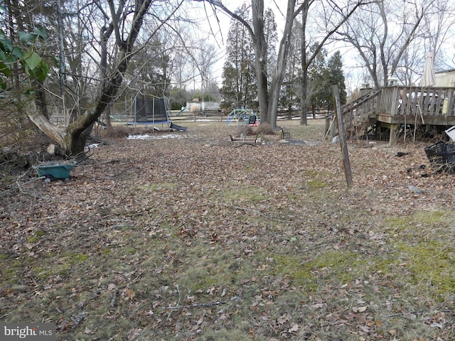 view of yard with a wooden deck and a trampoline