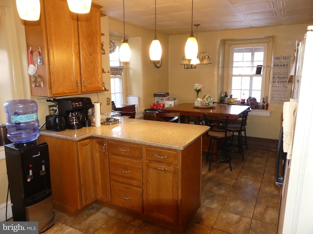 kitchen with light stone counters, plenty of natural light, decorative light fixtures, and kitchen peninsula