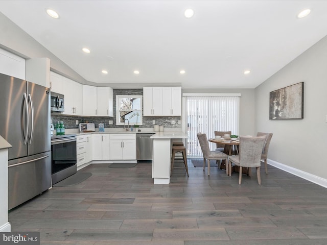 kitchen featuring lofted ceiling, a sink, light countertops, appliances with stainless steel finishes, and tasteful backsplash