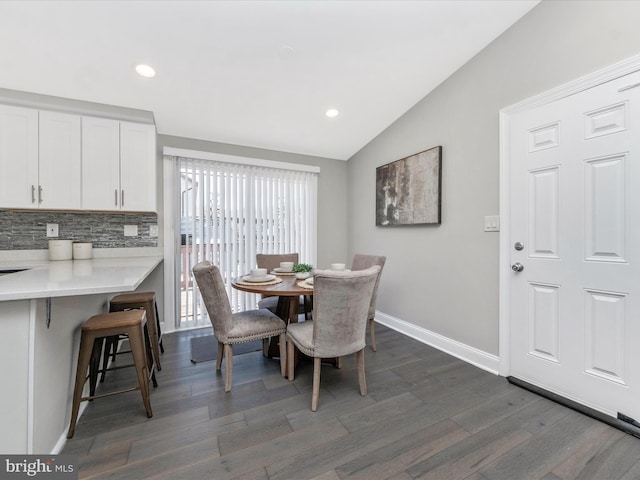 dining room with dark wood-style floors, lofted ceiling, baseboards, and recessed lighting