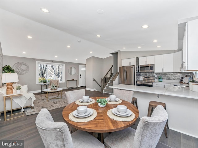 dining space with recessed lighting, dark wood-style flooring, vaulted ceiling, and stairway