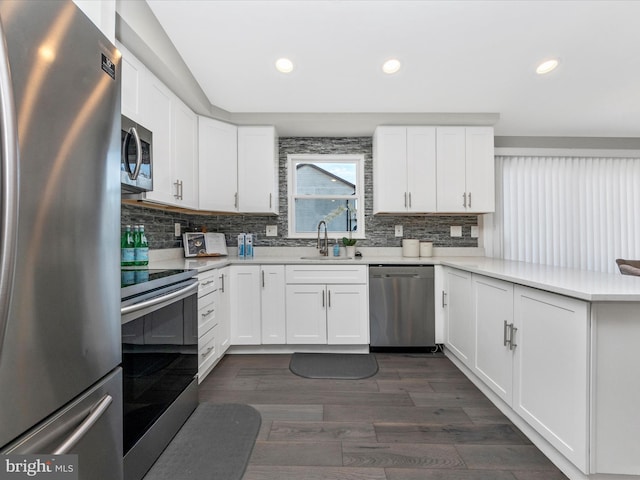 kitchen featuring dark wood-style floors, a peninsula, stainless steel appliances, light countertops, and a sink