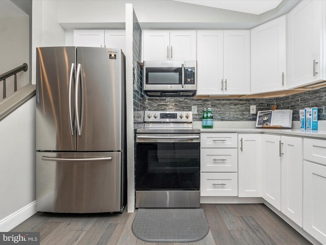 kitchen featuring tasteful backsplash, white cabinets, wood finished floors, stainless steel appliances, and light countertops