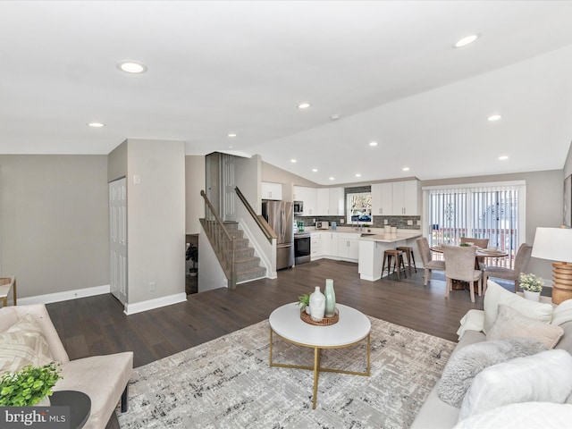 living area with dark wood-style floors, stairway, vaulted ceiling, and recessed lighting