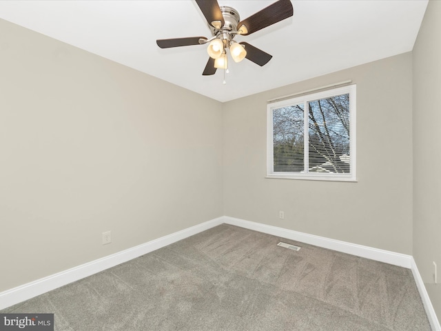 carpeted empty room featuring a ceiling fan, visible vents, and baseboards