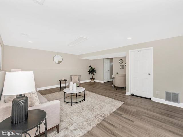 living room with recessed lighting, visible vents, baseboards, and wood finished floors