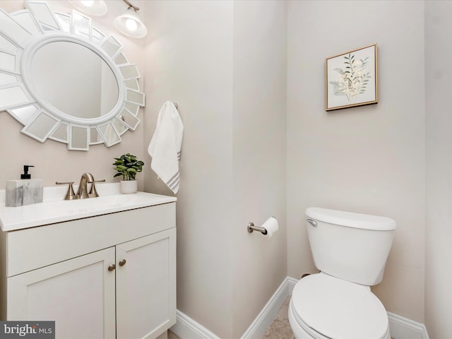 half bathroom with toilet, vanity, and baseboards