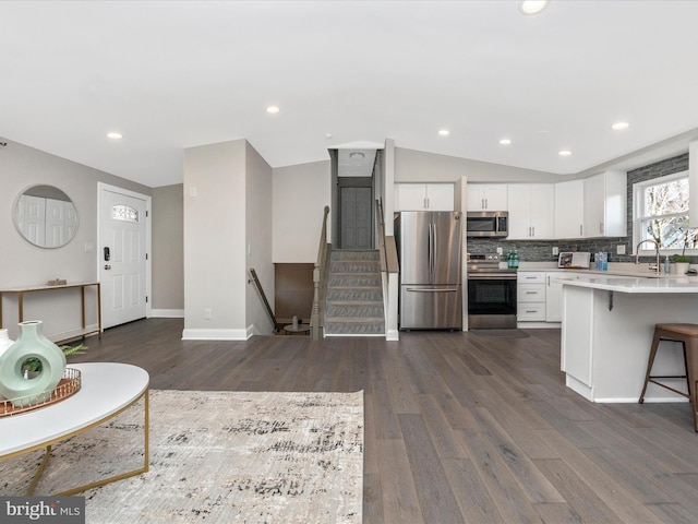 kitchen with white cabinets, appliances with stainless steel finishes, light countertops, and dark wood-style flooring