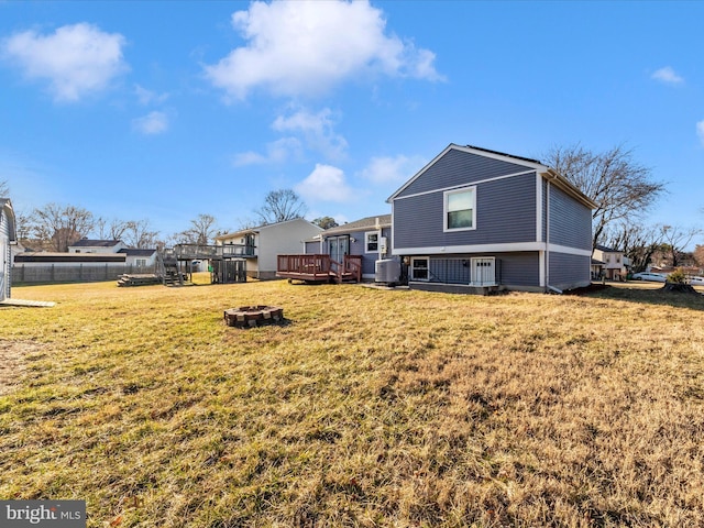 back of property with an outdoor fire pit, a lawn, fence, cooling unit, and a wooden deck