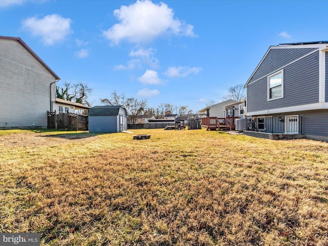 view of yard with an outdoor structure, fence, a deck, and a storage shed