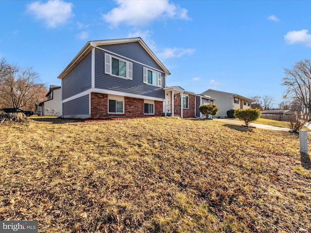 split level home featuring a front yard and brick siding