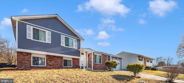 split level home featuring an attached garage, a front yard, and brick siding