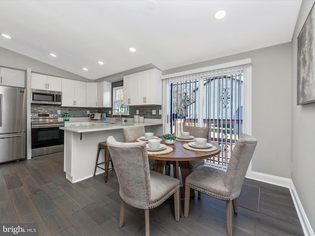 dining room with dark wood finished floors, vaulted ceiling, baseboards, and recessed lighting