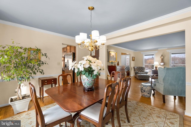 dining area with crown molding, an inviting chandelier, and light wood-type flooring