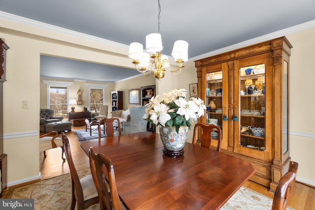 dining space featuring crown molding, a chandelier, and light wood-type flooring