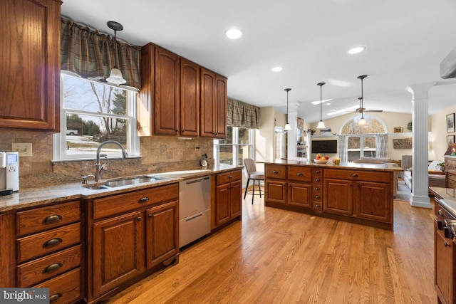 kitchen with sink, light wood-type flooring, stainless steel dishwasher, pendant lighting, and decorative columns