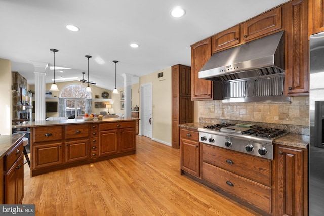 kitchen featuring stainless steel gas cooktop, extractor fan, vaulted ceiling, hanging light fixtures, and light hardwood / wood-style floors