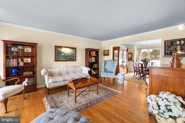 living room with crown molding, a notable chandelier, and light wood-type flooring