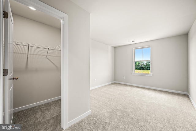 unfurnished bedroom featuring a spacious closet, carpet floors, and a closet