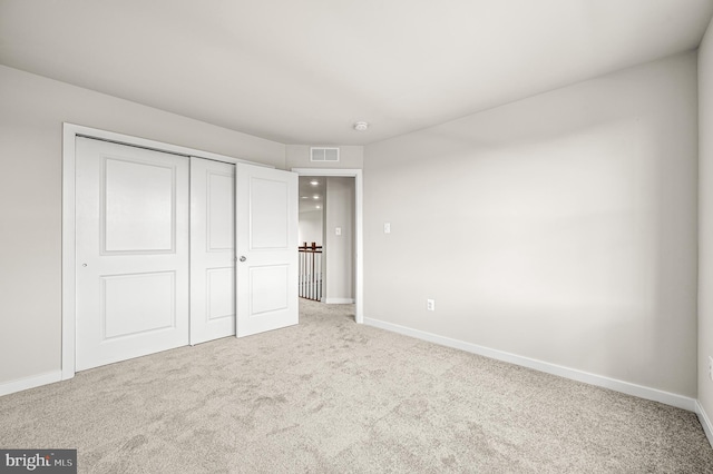 unfurnished bedroom featuring light colored carpet and a closet