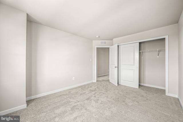 unfurnished bedroom with light colored carpet and a closet