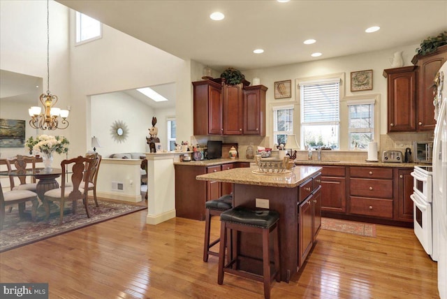 kitchen with double oven range, light hardwood / wood-style floors, hanging light fixtures, and a kitchen island