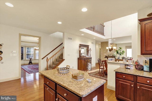 kitchen with a kitchen island, decorative light fixtures, an inviting chandelier, and light hardwood / wood-style floors