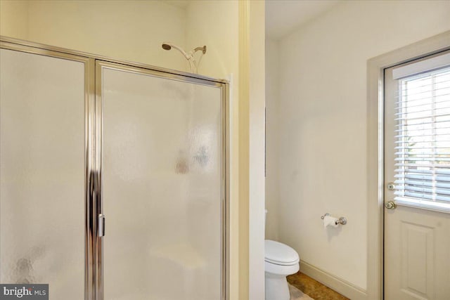 bathroom featuring toilet, a healthy amount of sunlight, tile patterned floors, and walk in shower