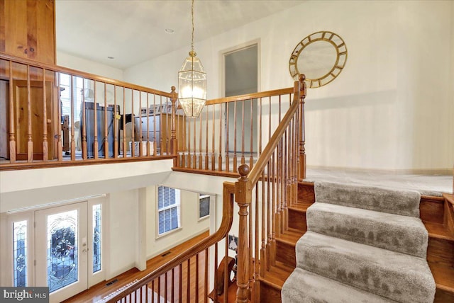 staircase featuring wood-type flooring and a notable chandelier