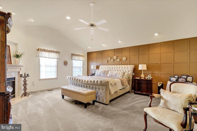 bedroom featuring a tile fireplace, lofted ceiling, light carpet, and ceiling fan