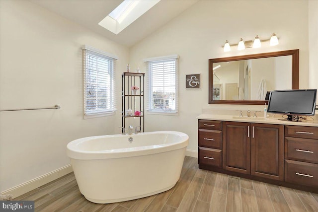 bathroom with vanity, vaulted ceiling with skylight, and a bathtub