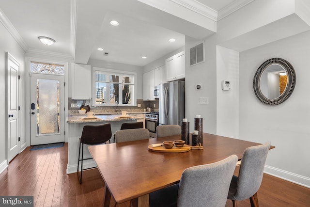 dining space featuring crown molding, dark hardwood / wood-style floors, and sink