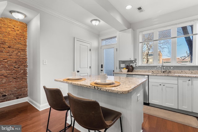 kitchen featuring sink, dishwasher, a kitchen island, light stone countertops, and white cabinets