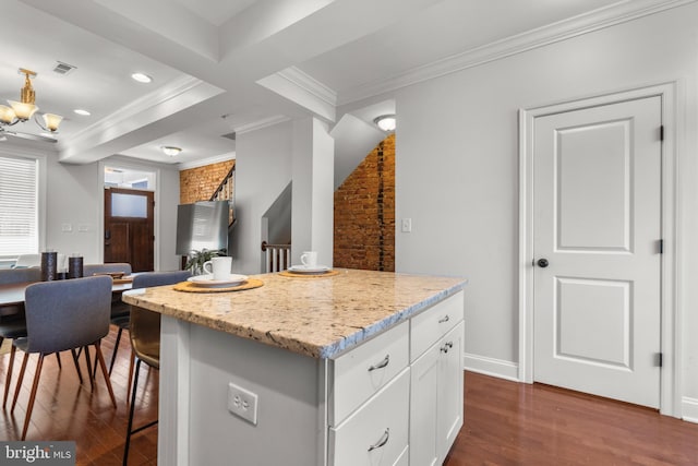 kitchen featuring a kitchen island, dark hardwood / wood-style floors, white cabinetry, ornamental molding, and light stone countertops