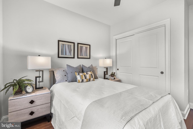 bedroom with dark wood-type flooring, ceiling fan, and a closet