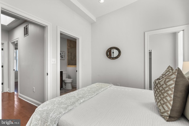 bedroom featuring connected bathroom and dark hardwood / wood-style flooring