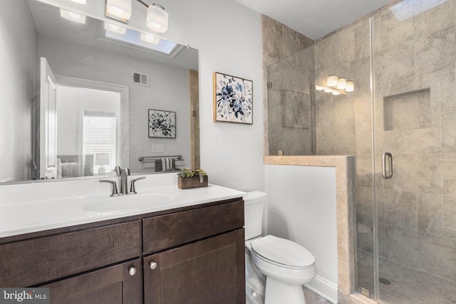 bathroom featuring vanity, toilet, and a shower with shower door