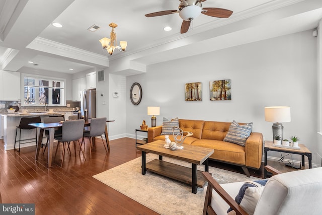 living room featuring ceiling fan with notable chandelier, ornamental molding, and dark hardwood / wood-style floors