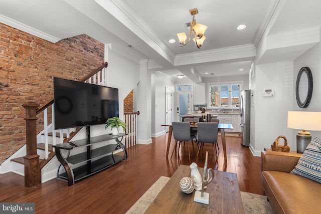 living room featuring sink, crown molding, an inviting chandelier, brick wall, and dark hardwood / wood-style flooring