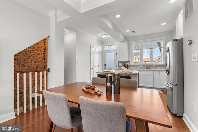 dining space with crown molding, wood-type flooring, and sink