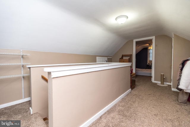 hall with vaulted ceiling and light carpet