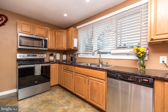 kitchen with sink, stainless steel appliances, and dark stone counters