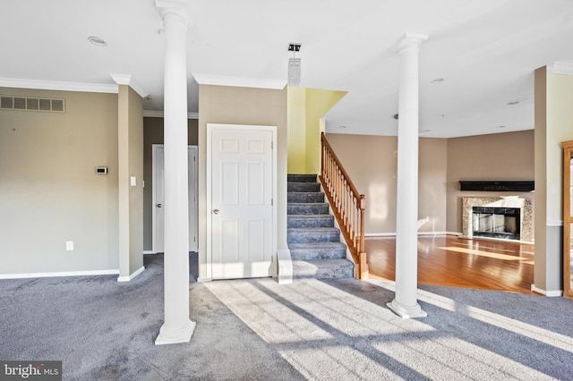 stairs with crown molding, carpet flooring, a premium fireplace, and decorative columns