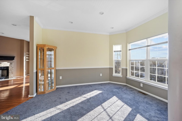 carpeted empty room with a premium fireplace and crown molding