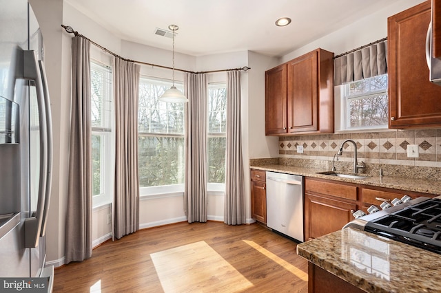 kitchen featuring sink, tasteful backsplash, decorative light fixtures, stainless steel dishwasher, and light stone countertops