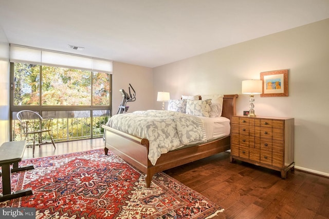 bedroom with dark hardwood / wood-style floors and expansive windows