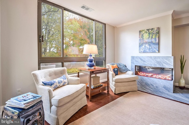 sitting room with crown molding, dark wood-type flooring, and a premium fireplace