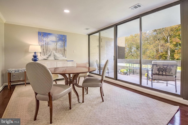 dining area with dark wood-type flooring, ornamental molding, and expansive windows