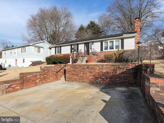 ranch-style home with brick siding and a chimney